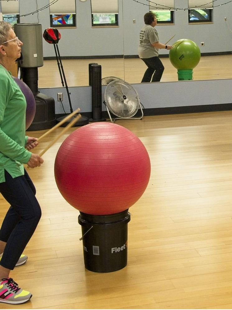 Women hitting large balls with drumsticks